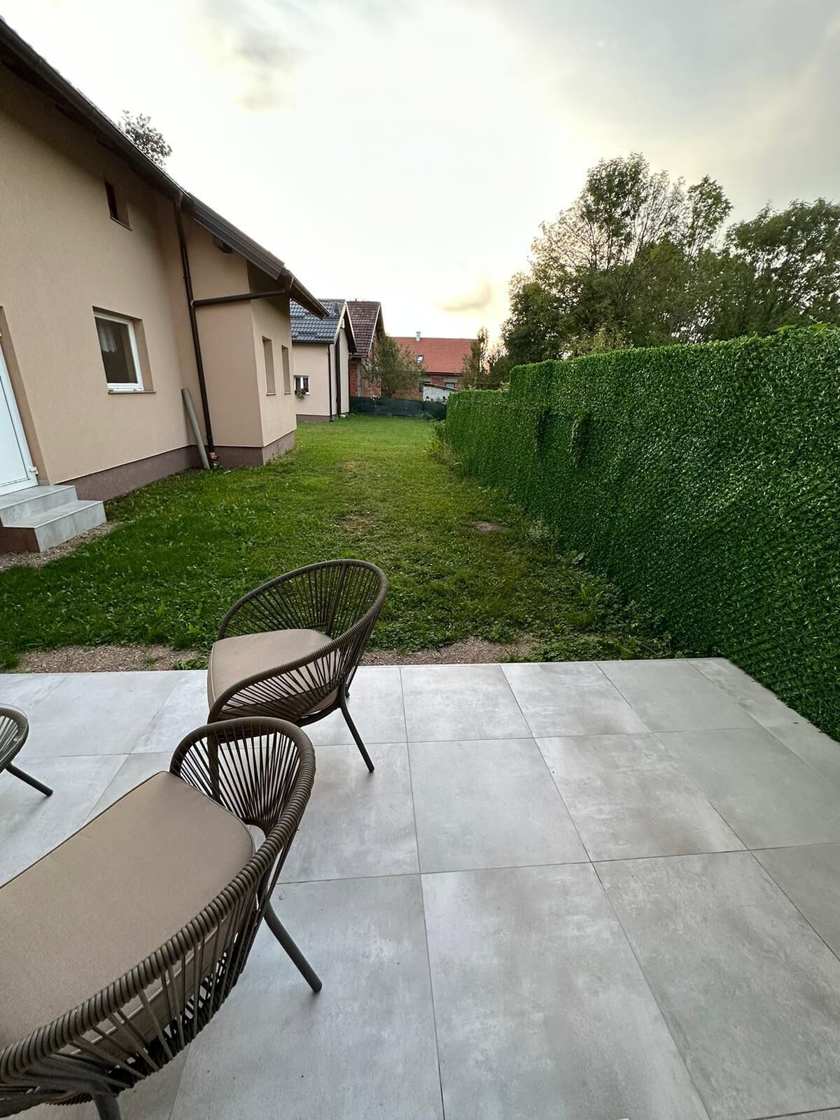 Un espace extérieur aménagé avec une table et des chaises, une pelouse bien entretenue et une haie.