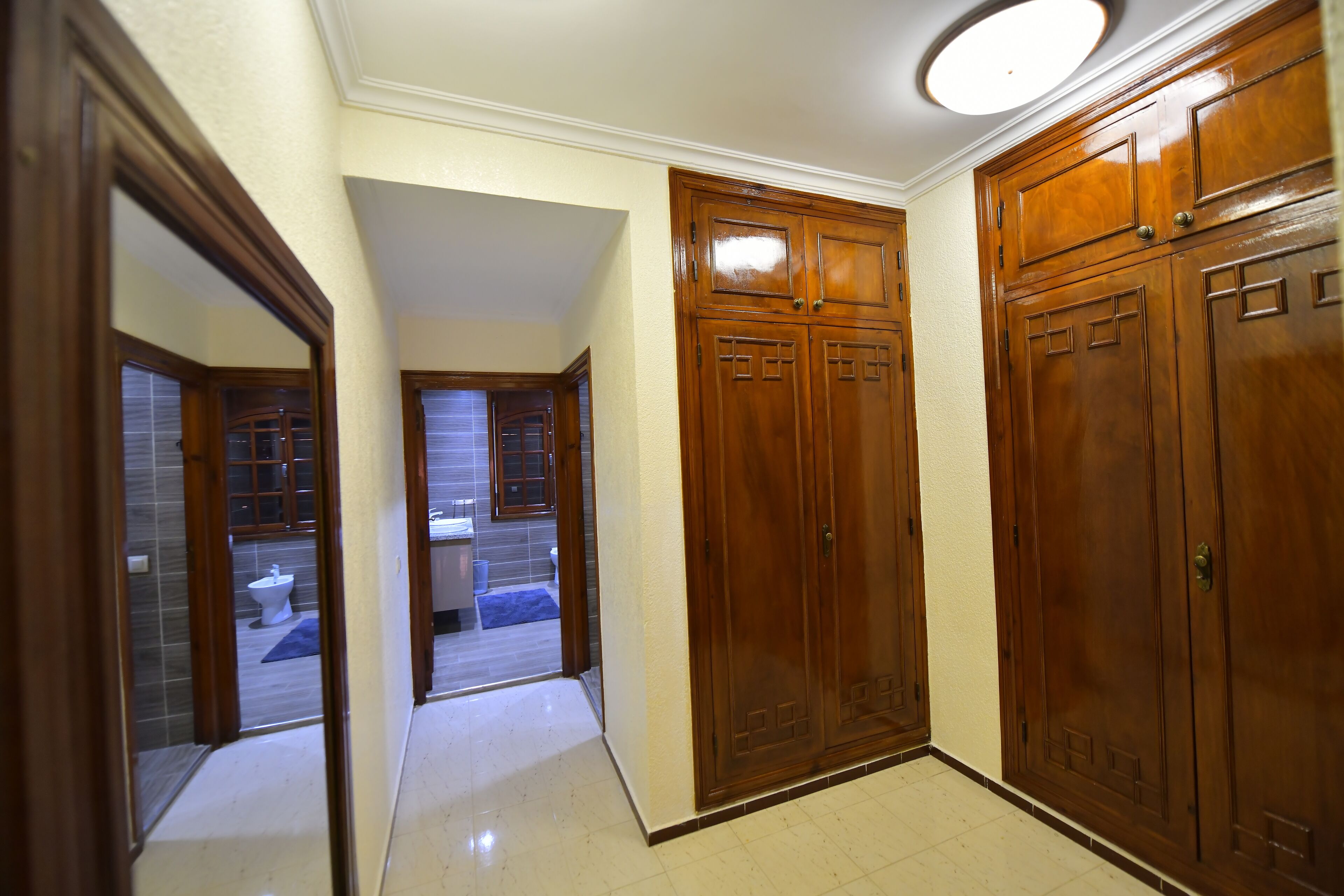 Un couloir avec des portes en bois et une salle de bain visible à travers une porte entrouverte.