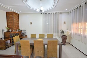 Un coin repas agrémenté d’une cheminée en briques, de chaises en osier, d’une table en bois et d’un vase décoratif.