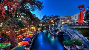 A riverside walkway with outdoor seating and a bridge. - Remodeled Historic 1BR 1BA House Near Downtown (San Antonio)