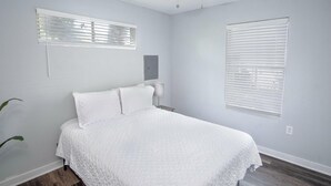 A bedroom with a bed, a ceiling fan, and two windows with blinds. - Remodeled Historic 1BR 1BA House Near Downtown (San Antonio)