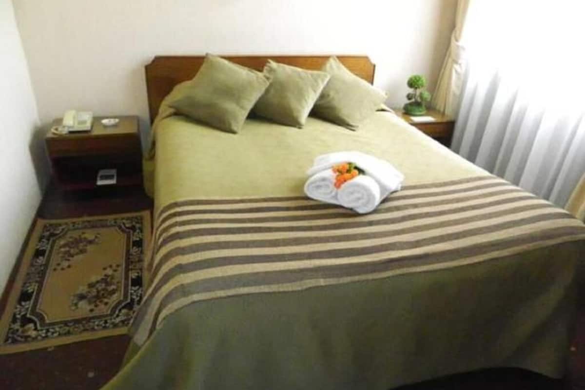 Un lit bien fait, avec une couverture à rayures, des oreillers et une serviette enroulée posée sur le lit.