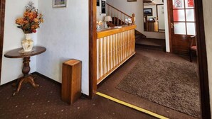 A hotel lobby with a reception desk, a wooden counter, a small round table with a vase of flowers, and a carpeted floor. - HOTEL MERCURIO (Punta Arenas)
