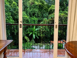 Ein Balkon mit Blick auf üppiges Grün, einem Metallgeländer und einem gefliesten Boden.