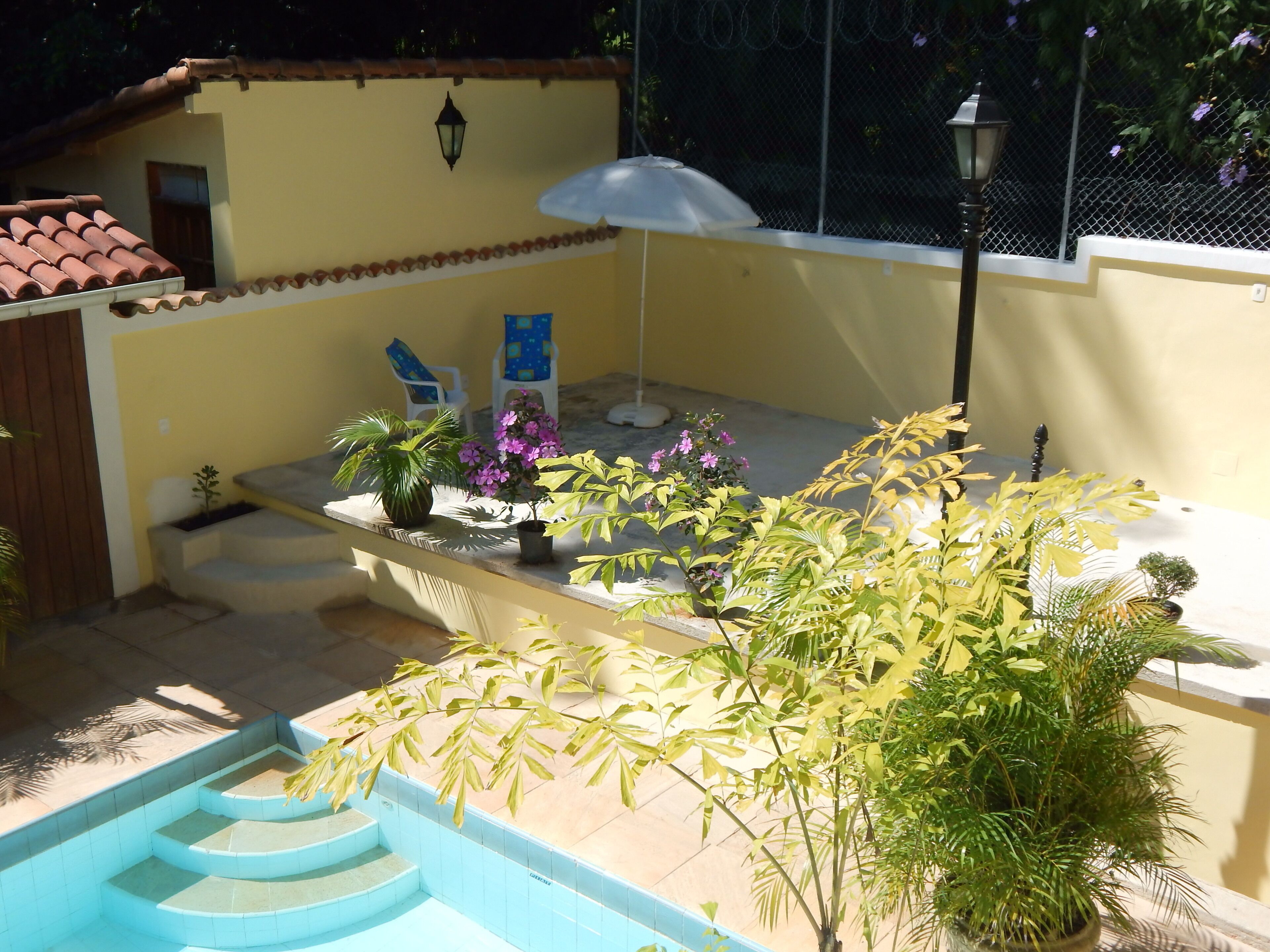 Ein Poolbereich mit Stufen zum Wasser, umgeben von Topfpflanzen und Gartenmöbeln.