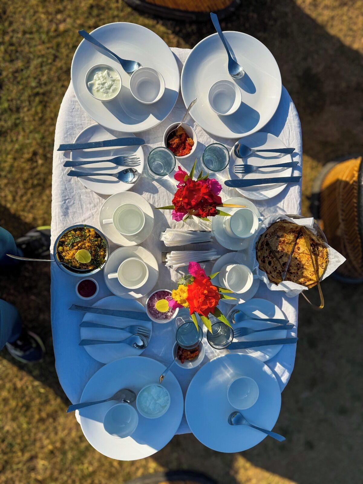 Une table mise pour un repas, avec différents plats, couverts et un arrangement floral.