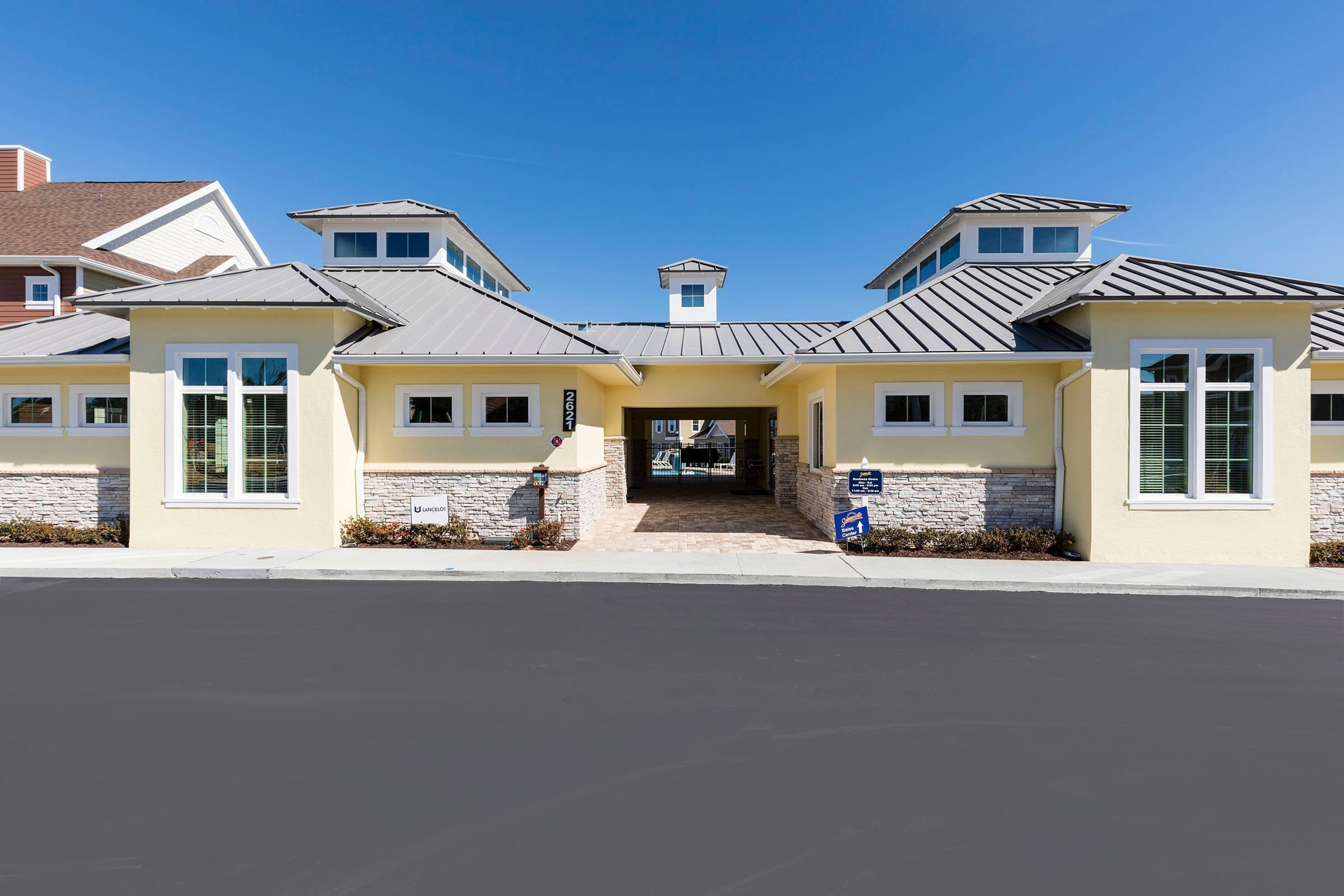 A modern building with a central entrance, stone accents, and a clear blue sky.