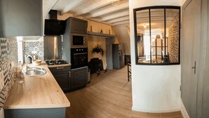 Una cucina moderna con un piano di lavoro in legno, elettrodomestici in acciaio inossidabile e vista sull'area soggiorno tramite una finestra.