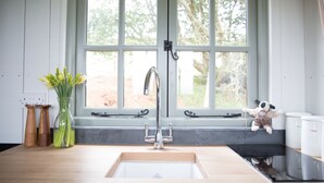 A kitchen with a large window, a sink, and a window sill with a dog figurine. - Shepherd Hut with free Hot Tub, Wifi and Breakfast Hamper. (West Bagborough)