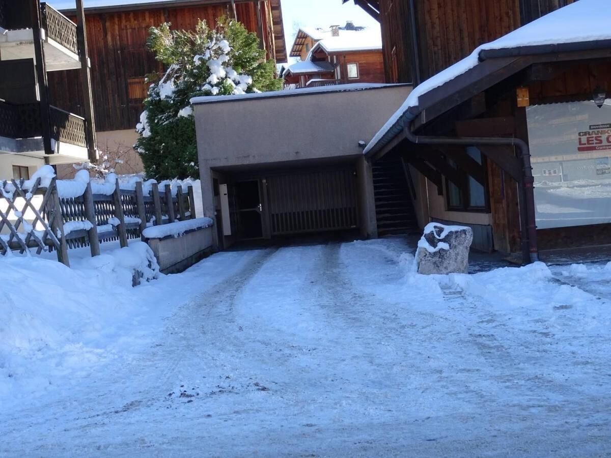 Ein verschneiter Weg führt zu einem Gebäude mit einer Holzfassade.
