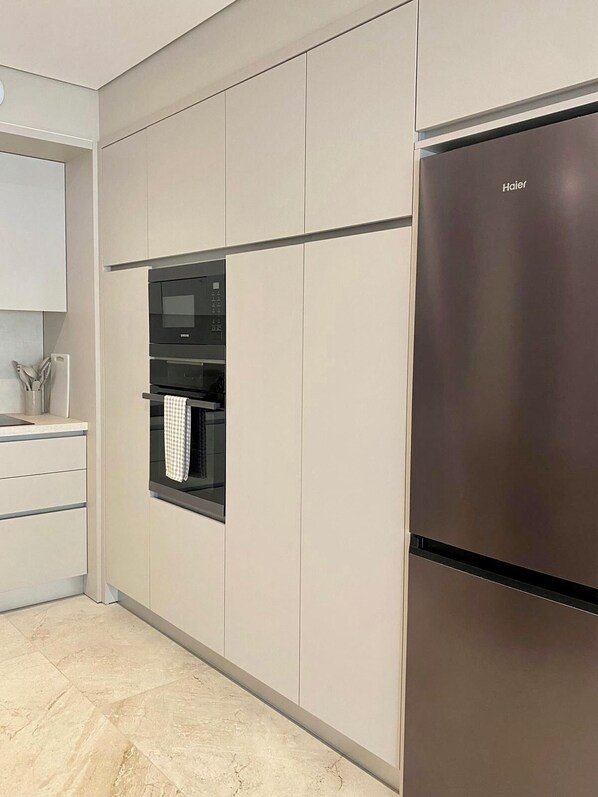 A modern kitchen with a stainless steel refrigerator, built-in oven, and microwave. - Apartment no. 104 (Zonza)