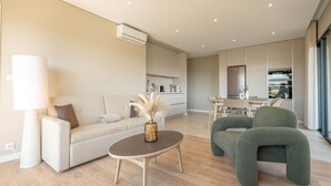 A modern living room with a sofa, a round coffee table, and a green armchair.