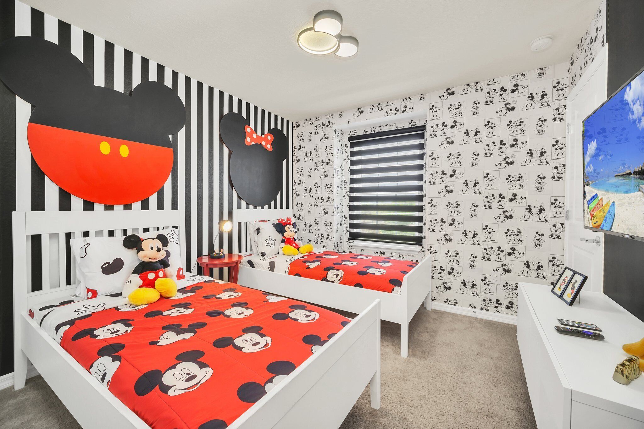 Ein Kinderzimmer mit Bettwäsche und Wandgestaltung im Mickey Mouse Design, inklusive eines Bettes mit Mickey Mouse Kopfteil.