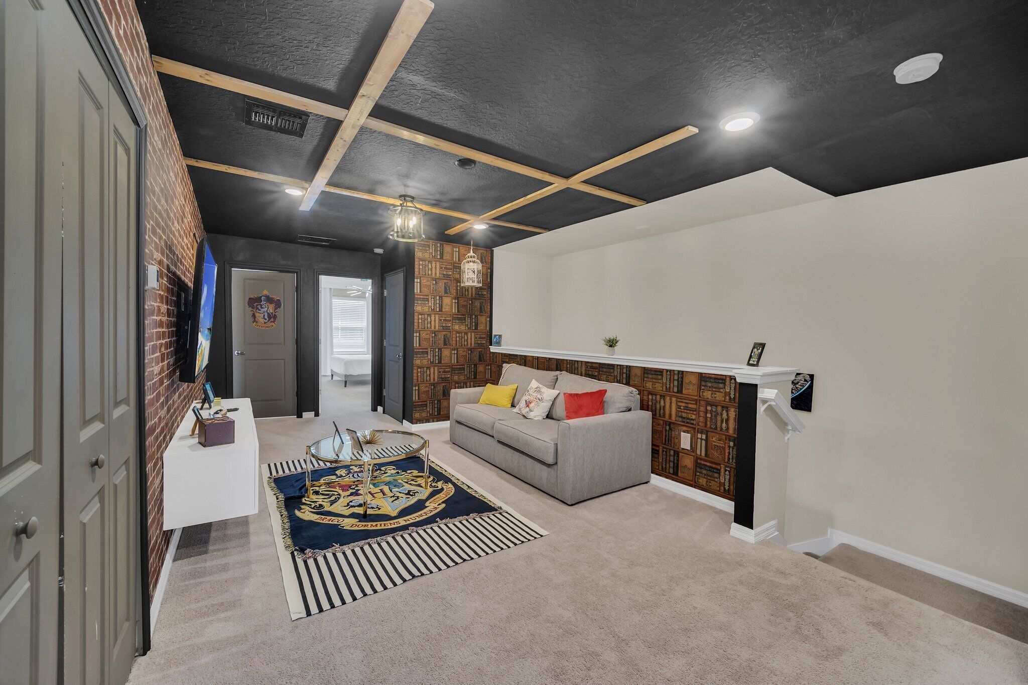 Un interno domestico con un divano grigio, un tappeto decorato e una libreria a parete.