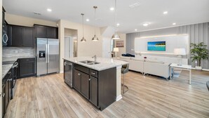 A modern kitchen with dark cabinets, stainless steel appliances, and a granite countertop. - EV_1721 - 5BR & 4BR w Screened-In Private Pool, Games Room, Kids Bedroom, Resort (Davenport)