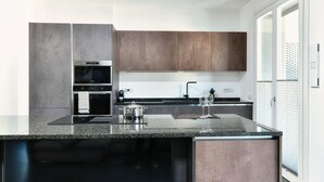 A modern kitchen with granite countertops, stainless steel appliances, and wooden cabinets. - Como in Centro (Como)