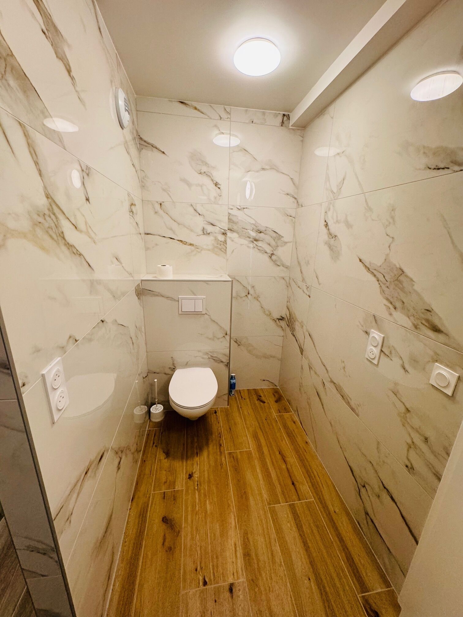 Ein kleines, modernes Badezimmer mit Toilette, Waschbecken und Dusche.