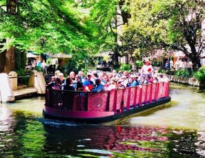 Un bote estrecho con pasajeros, rodeado de vegetación y agua.