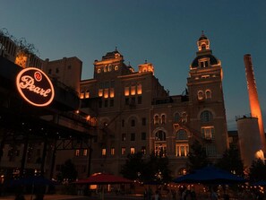Un edificio histórico con ventanas iluminadas y una imponente torre del reloj, rodeado de terrazas al aire libre.