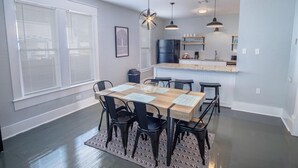 A dining area with a wooden table and black chairs, a kitchen with a black refrigerator and a sink, and a window with blinds. - Wonderful 3 BR 2 BA Near Downtown (San Antonio)