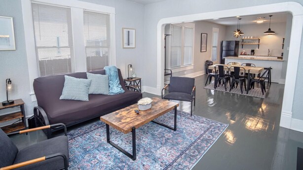 A living room with a sofa, coffee table, and chairs, a dining area with a table and chairs, and a kitchen with a fridge and counter. - Wonderful 3 BR 2 BA Near Downtown (San Antonio)