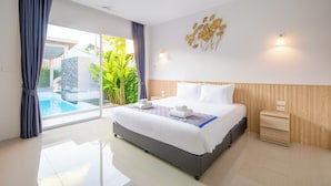 A modern hotel room with a large bed, a bedside table, a small bedside lamp, and a view of a swimming pool. - Sasi Pool Villa Phuket (Rawai)