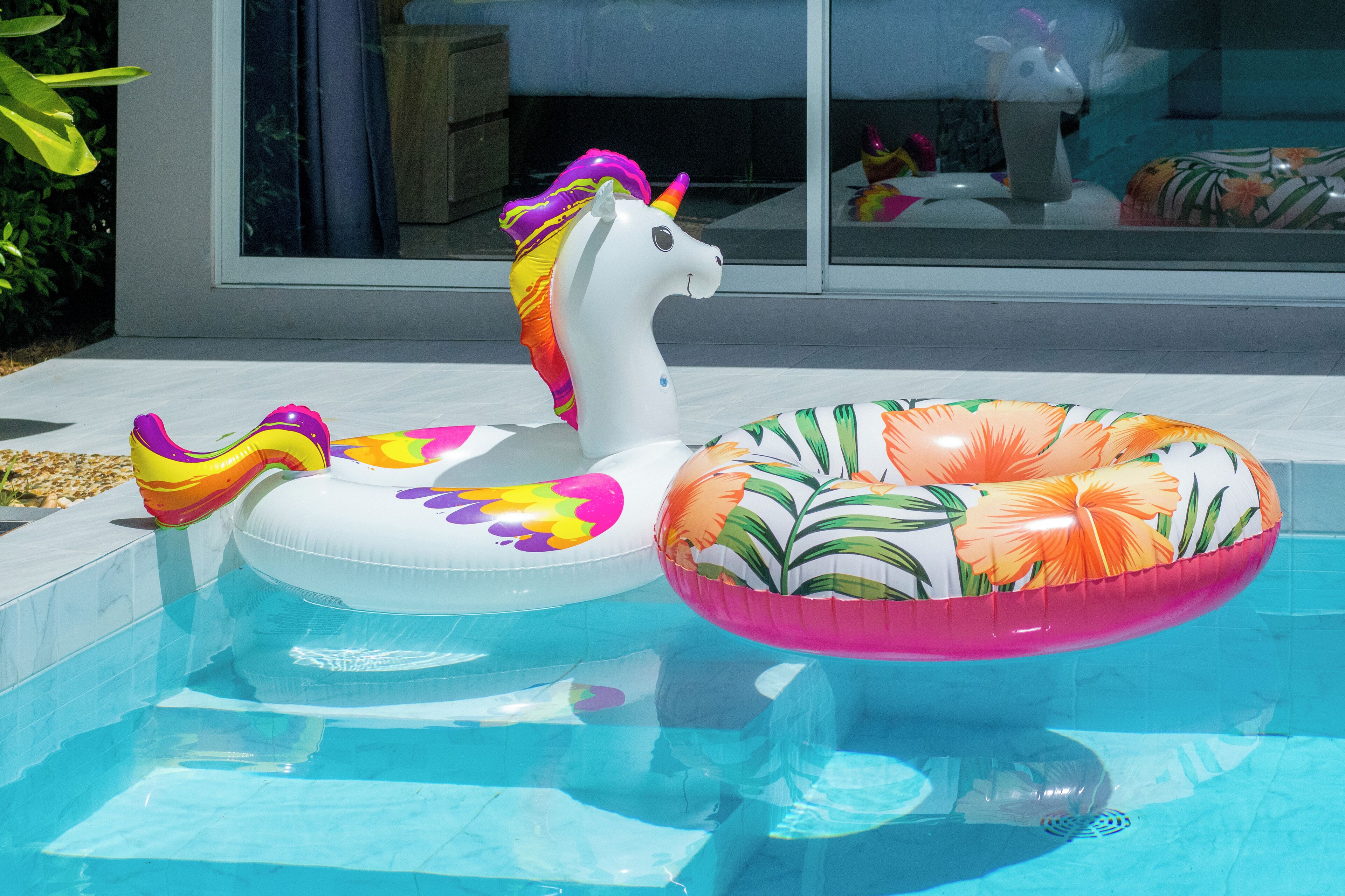 Une piscine avec des jouets gonflables, notamment une bouée en forme de licorne et une autre en forme de flamant rose.