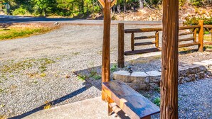 Ein hölzernes Pavillon mit Bänken und einem Picknicktisch, umgeben von Kies und Grünpflanzen.