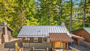 Eine rustikale Holzhütte mit Metalldach, einer Holzveranda und Kiesgrundstück.