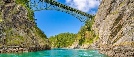 A bridge over a turquoise river with rocky cliffs on either side.