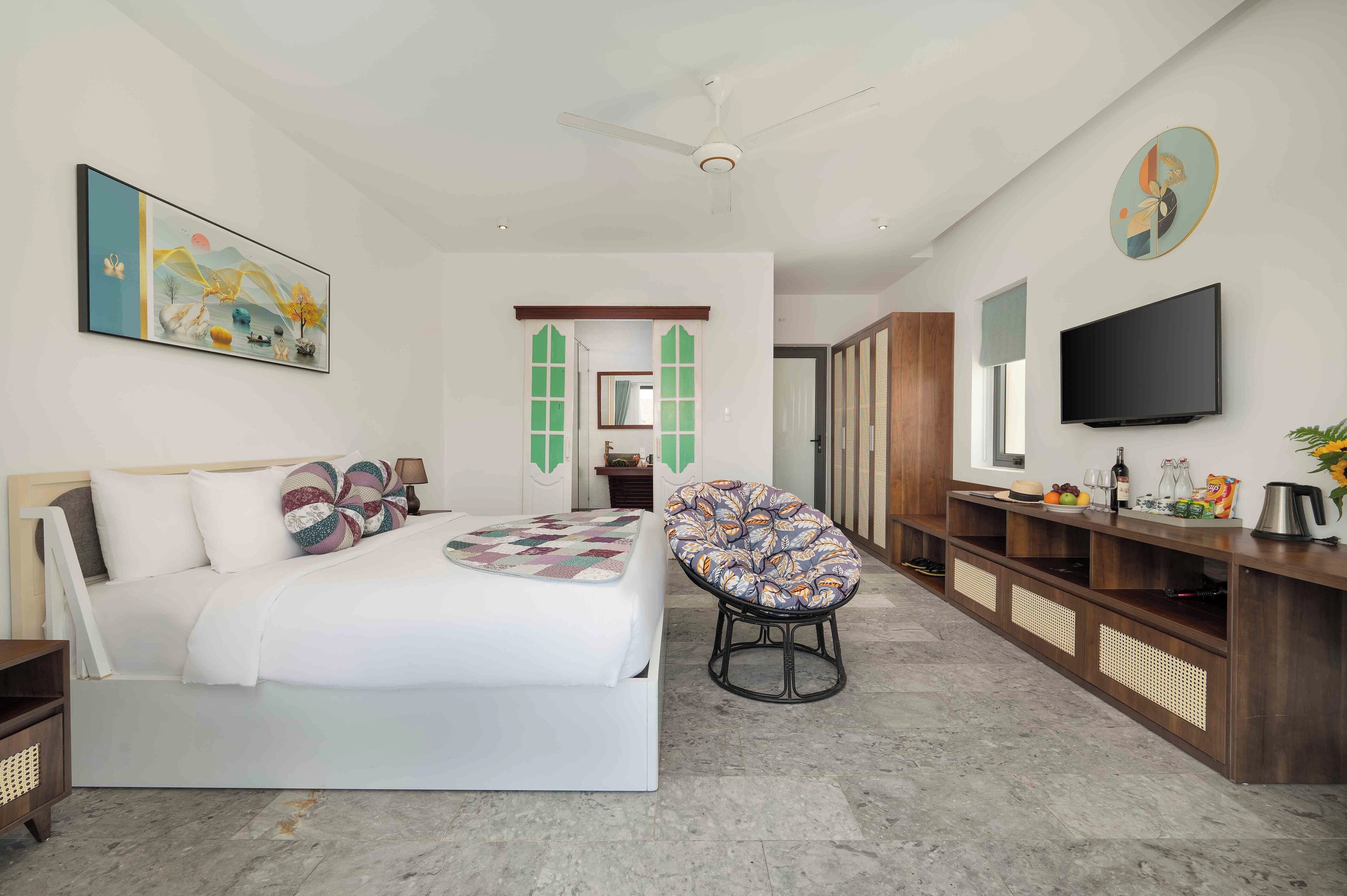 Een moderne hotelkamer met een groot bed, een zithoek, een televisie en een ontbijtcounter.