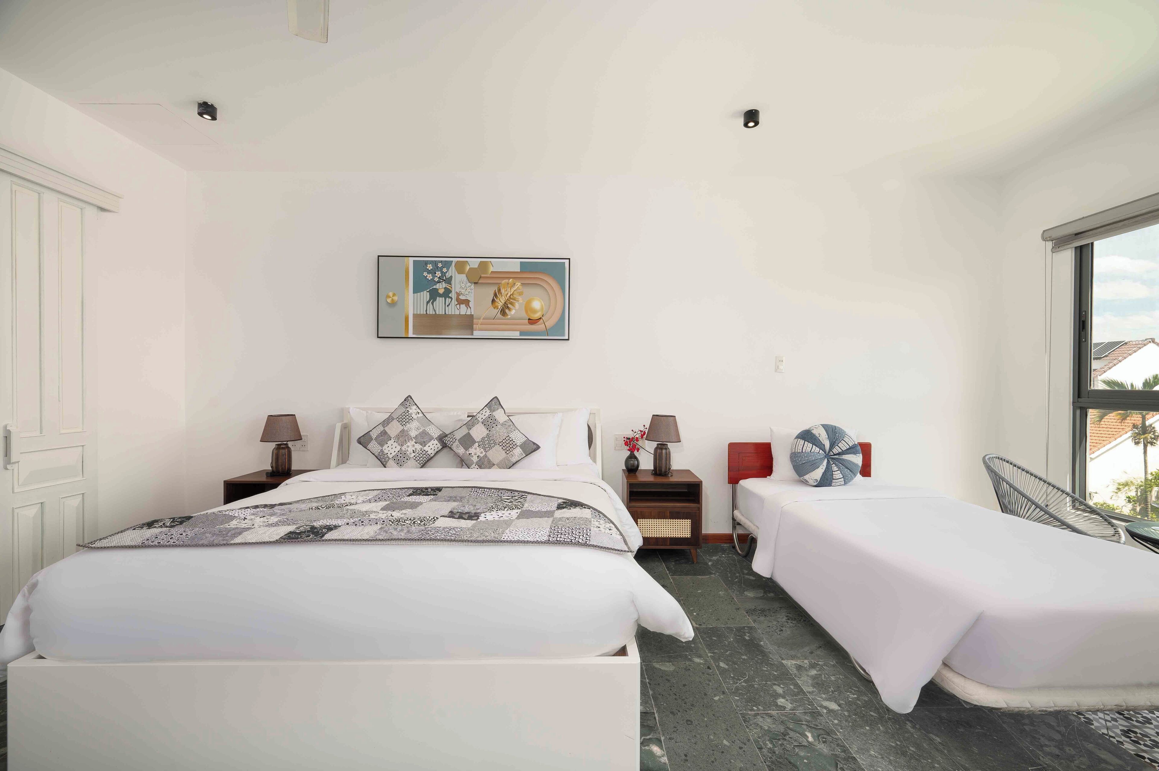 A modern bedroom with a large bed, two bedside tables, a small table, and a chair.