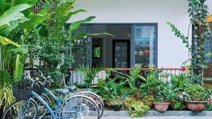 Una bicicleta estacionada en un jardín con plantas en macetas y un edificio al fondo.