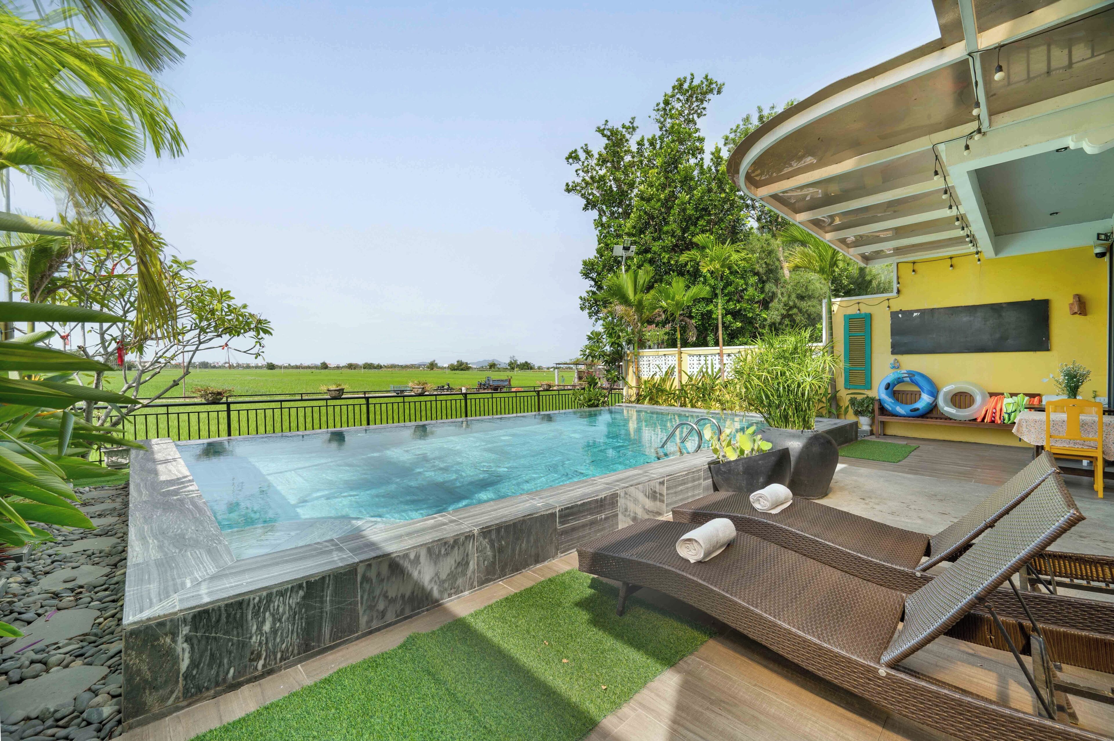 Una piscina al aire libre, sombrillas, sillones reclinables de piscina