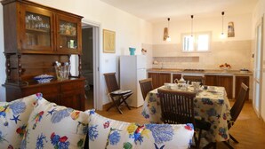 A cozy kitchen with wooden cabinets, a dining table with chairs, and a refrigerator. - Villa Agapanto - Trullo Agap con Vista Mare e Giardino Privato (Tricase)