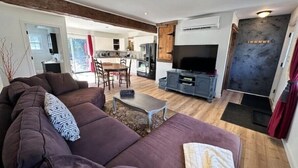 A modern living room with a large sectional sofa, a dining area, and a kitchen in the background. - A Country Stay Just Minutes Away
 (Cambridge)