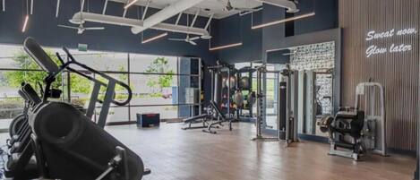 A gym with various exercise equipment, large windows, and a motivational quote on the wall.