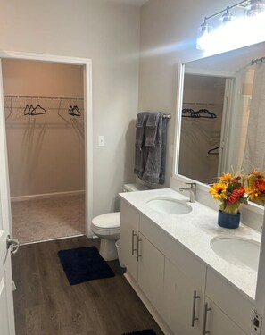 A bathroom with a white sink, two mirrors, a towel rack, and a shower area.