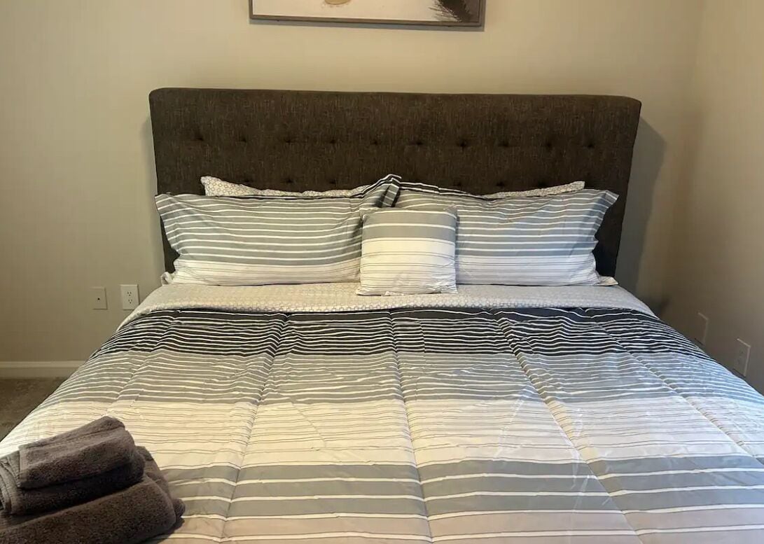 A neatly made bed with striped bedding and a tufted headboard.