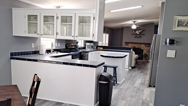 Una cocina moderna con armarios blancos, una isla central y una zona de comedor con una mesa y sillas de madera.