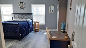 Un dormitorio con una cama, una mesita, una silla, una ventana y una puerta.