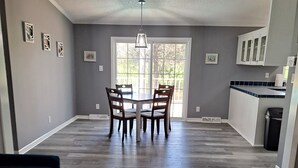 Un salón amplio con piso de madera oscura, un sofá azul y una mesa de comedor con sillas.