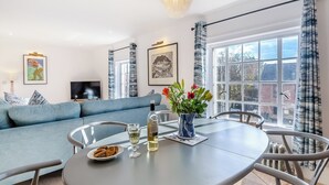 Un salon moderne avec une table à manger ronde, un canapé bleu et une grande fenêtre avec des rideaux.