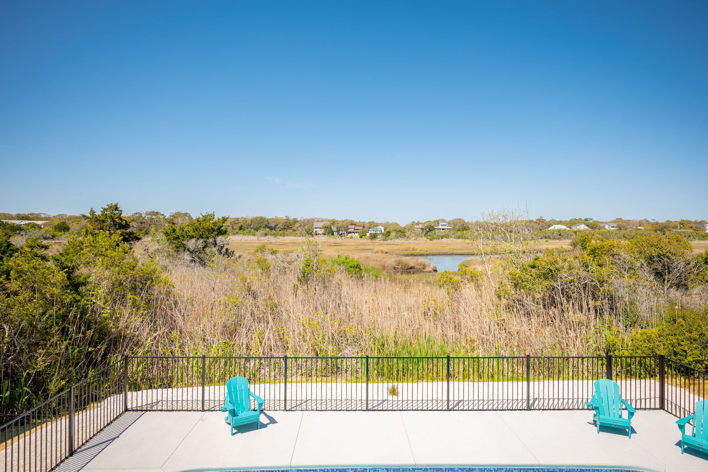 A pool area with a clear view of a lake and surrounding landscape.