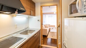 A modern kitchen with a built-in stove, a microwave, and a refrigerator. - Tsutenkaku Royal House (Osaka)