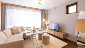 A modern living room with a sofa, dining table, TV, and a small cabinet. - Tsutenkaku Royal House (Osaka)