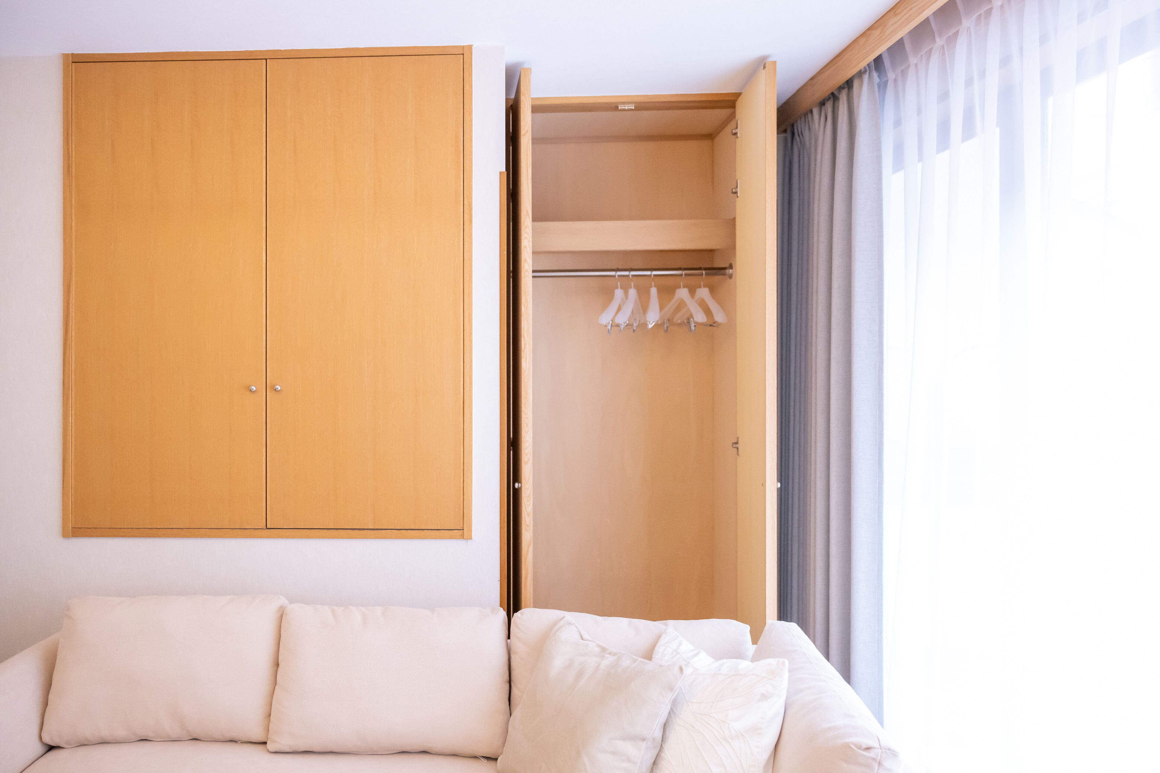 A room with a bed, a wooden wardrobe, and a clothing rack.