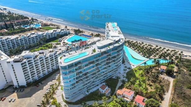 Ein Wolkenkratzerhotel mit mehreren Balkonen, einem Pool und Blick auf den Strand.