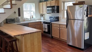 Une cuisine moderne avec des meubles en bois, des appareils en acier inoxydable et un îlot central en bois doté de tabourets.