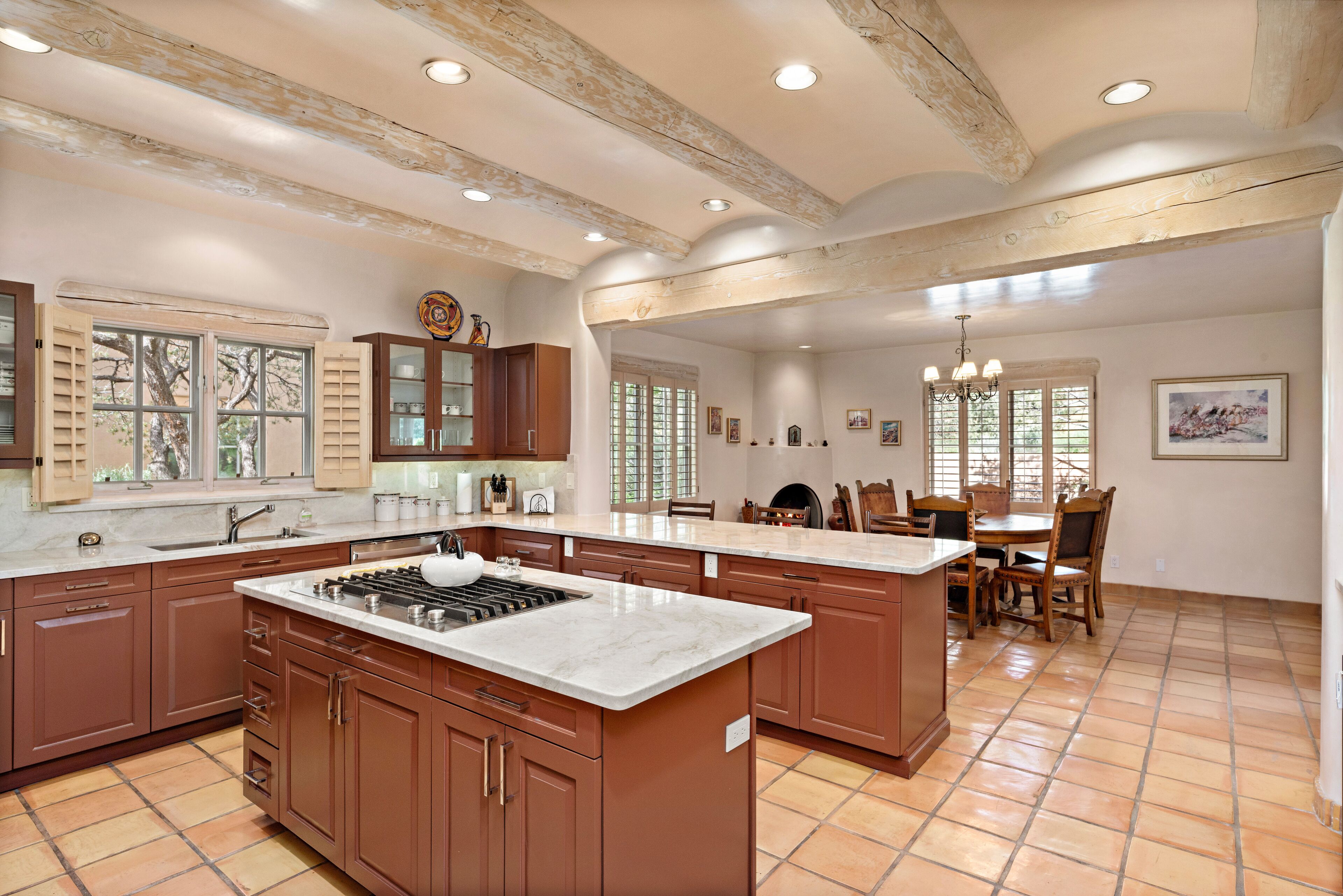 A spacious kitchen with a large island, wooden cabinets, and a tiled floor.